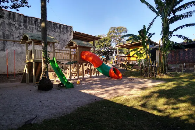 Brinquedão de madeira com dois escorregadores e casinha, na área de areia do quintal