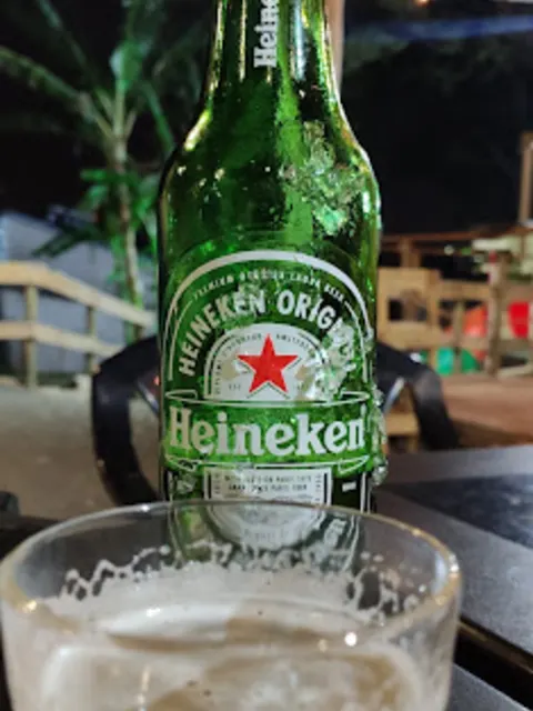 Garrafa de Heineken gelada ao lado de um copo cheio, à noite no quintal