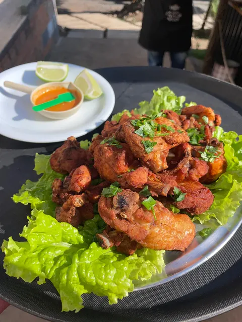 Travessa de frango a passarinho frito sobre alface, com limão e molho