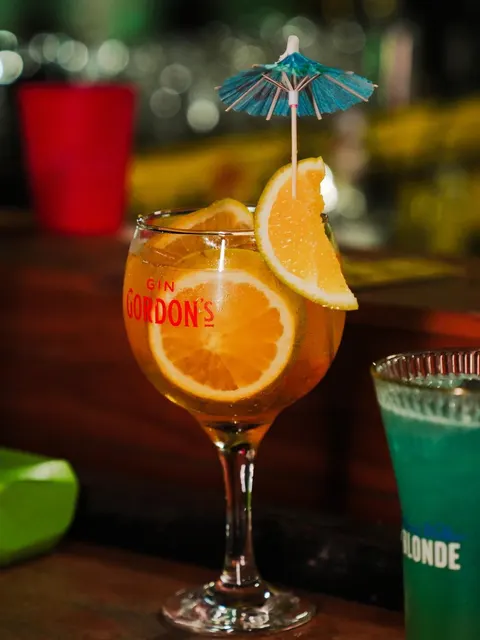 Taça de gin alaranjado com rodelas de laranja e sombrinha de papel