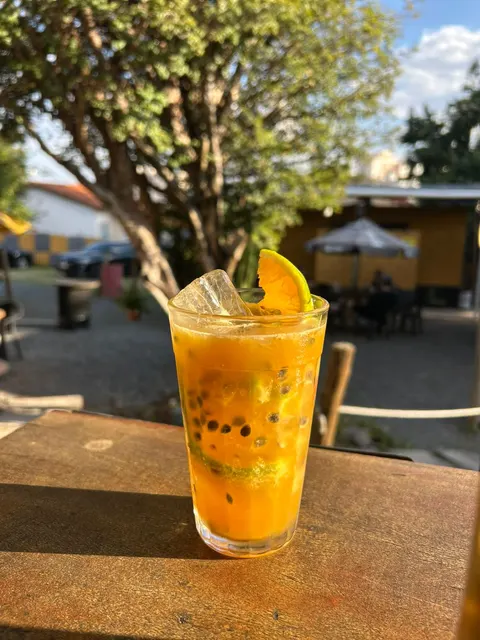 Copo de caipiroska de maracujá com rodela de laranja, ao sol do quintal